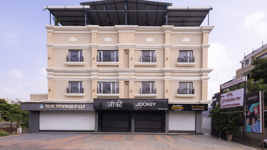 Exterior full view of the three-storey building of Pravasa Stay Luv Kush, Indore with storefronts visible.