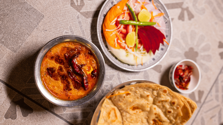 View of a flatbread dish, possibly a main course, with small side dishes at Pravasa Stay Luv Kush, Indore.