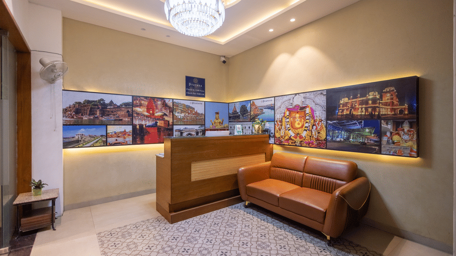 Interior view of the reception area showing a seating arrangement and decorative wall art at Pravasa Stay Luv Kush, Indore.