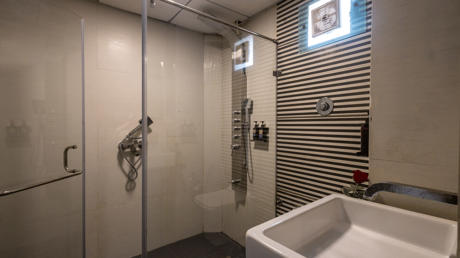 Modern hotel bathroom with a walk-in shower area, large white basin, and striking grey-and-white patterned wall tiles at Pravasa Stay, Vadodara.