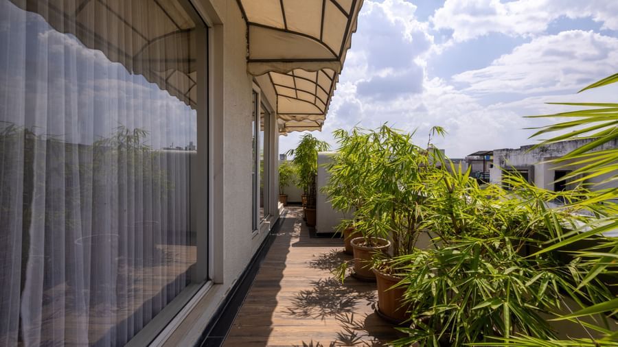 Balcony of a Suite in Pravasa Stay Vijay Nagar, Indore, seen with potted plants, spacious walkway under a cloudy sky.