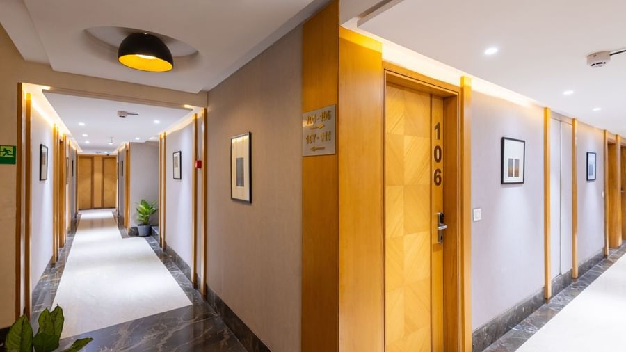 Common, spacious corridor of Pravasa Stay Vijay Nagar, Indore, furnished with potted plants, ample lighting, and marble flooring.