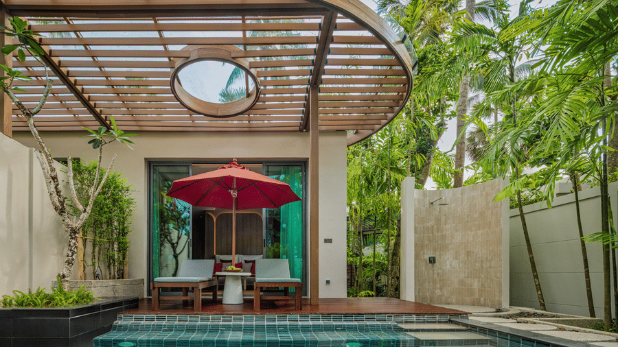 A view of an outdoor pool of Private Pool Villa at Ramada Resort with a shaded seating area, greenery, and a covered pergola.