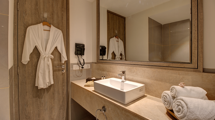 overview of the bathroom with a bathrobe kept on a hanger at Rhythm Gurugram