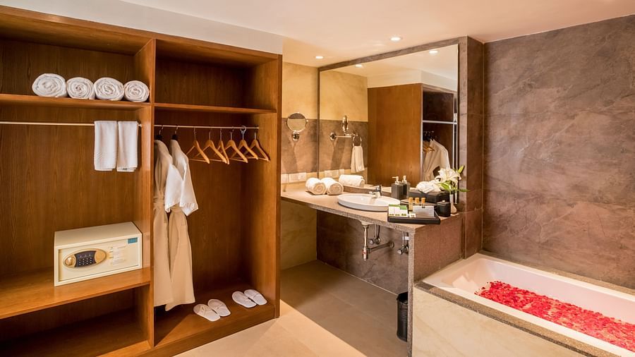 Washroom with a wooden cupboard featuring hangers with towels, bathrobes, and shoes arranged neatly.