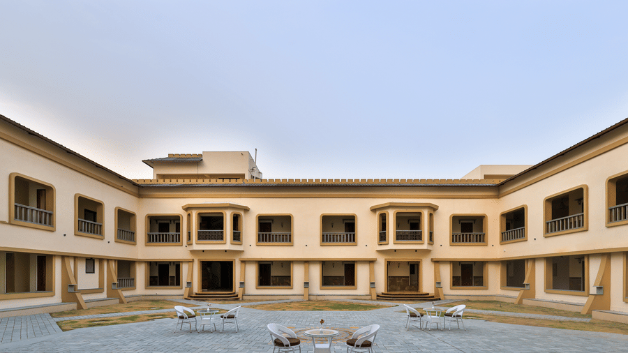 An open-air central courtyard with outdoor dining tables surrounded by the resort's multi-storey wings - Tathastu Chavri Resort, Jawai