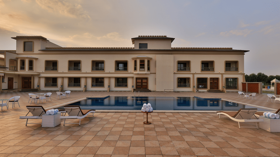 A view of the two-storey resort building facing the swimming pool area at dusk - Tathastu Chavri Resort, Jawai