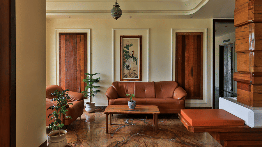 An interior view of a comfortable lobby featuring leather sofas, a wooden coffee table, and large windows - Tathastu Chavri Resort, Jawai