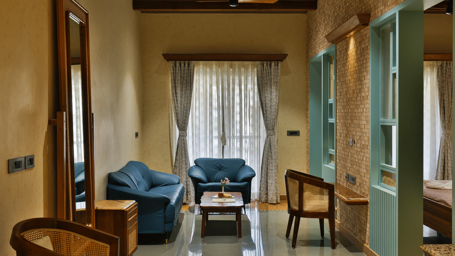 A spacious living area within a suite featuring blue sofas, a coffee table, and large curtains - Tathastu Chavri Resort, Jawai
