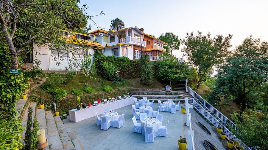 An open dinning area surrounded by trees at Te Aroha By Shervani, Mukteshwar