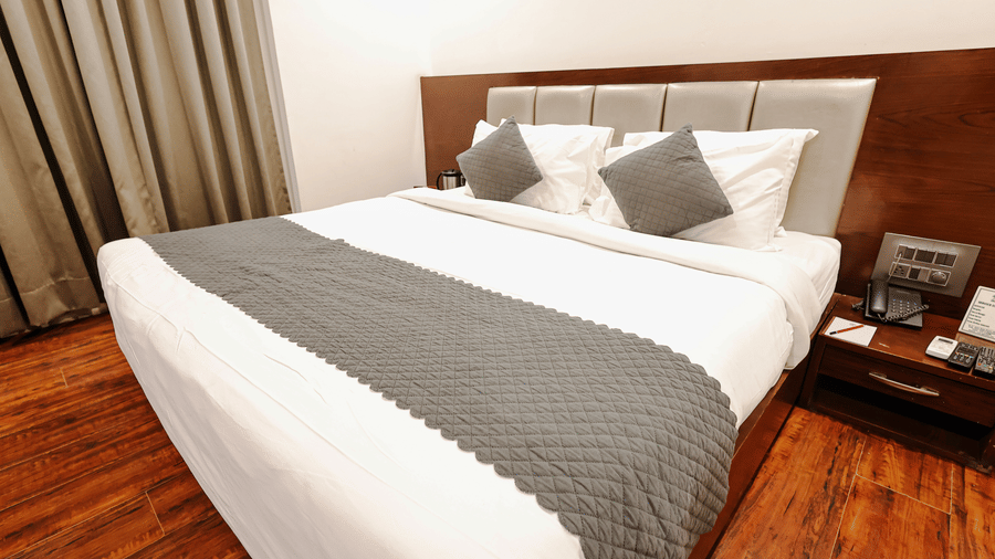 Executive Room at TGI Apple Inn, Ajmer Road, Jaipur featuring a bed, headboard, pillows, and a table with a telephone.