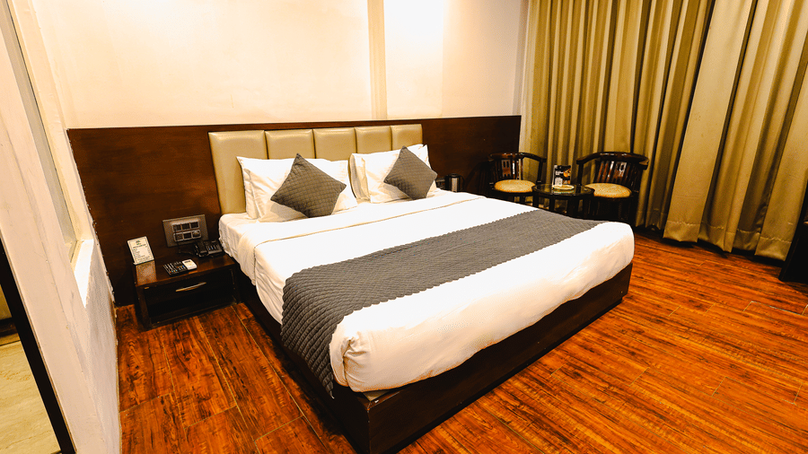Royal Executive Room at TGI Apple Inn, Ajmer Road, Jaipur featuring a bed with pillows, headboard, curtains, chairs, bedside table, and mirror.