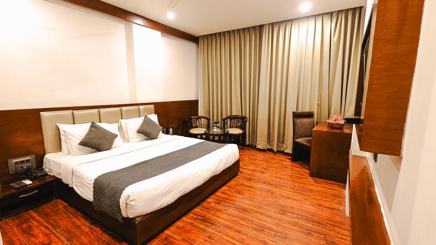Royal Executive Room at TGI Apple Inn, Ajmer Road, Jaipur featuring a bed with pillows, curtains, desk, chair, and bedside tables.