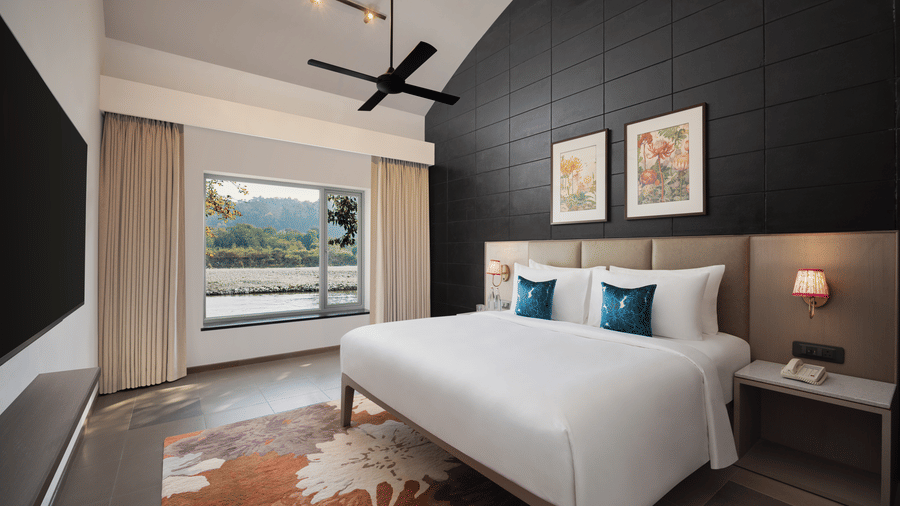 Elegant bedroom with plush bed, dark accent wall, ceiling fan, and scenic window view at The Corbett Hideaway.