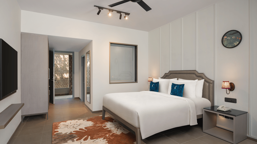 Minimal bedroom with comfortable bed, bedside lamp, wall decor, and open layout at The Corbett Hideaway.
