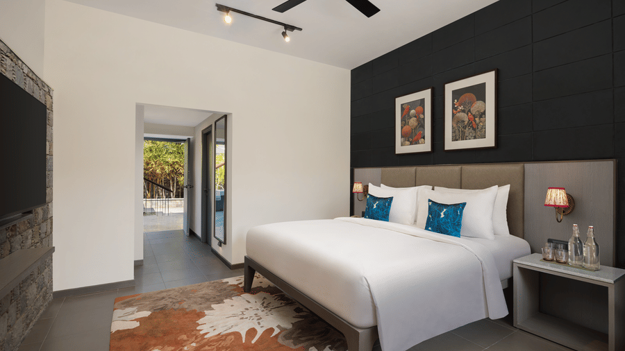 Modern bedroom with king-size bed, dark accent wall, bedside lamps, and minimalist decor at The Corbett Hideaway.
