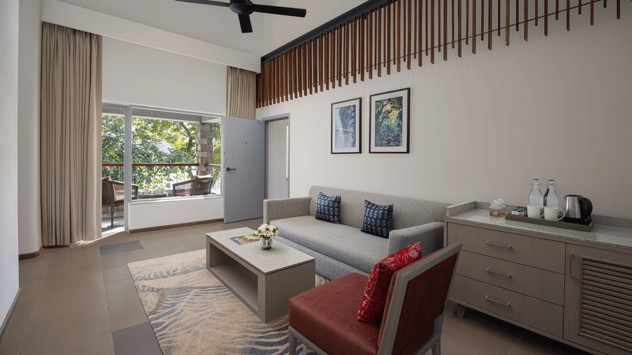Bright living area with sofa, armchairs, TV unit, and large window bringing in natural light at The Corbett Hideaway.