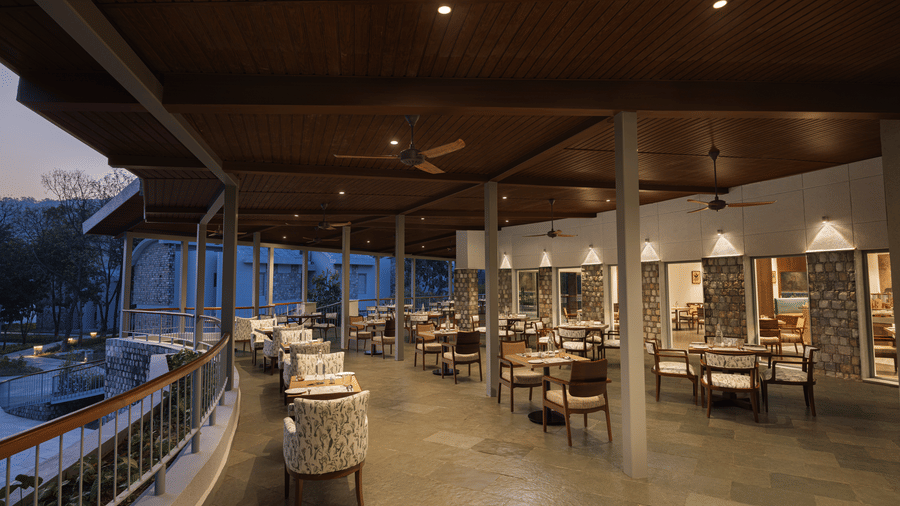 Open-air restaurant with wooden ceiling, warm lighting, and spacious seating arrangement at The Corbett Hideaway.