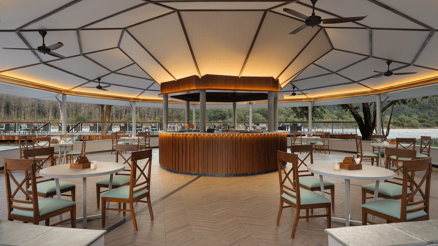 Covered restaurant with circular bar, wooden interiors, and open seating arrangement at The Corbett Hideaway.