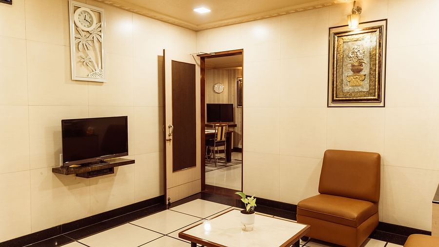 image of the living room of the grand suite highlighting a centre table in the middle with a small television at The Grand Krishna Rooms, Bengaluru