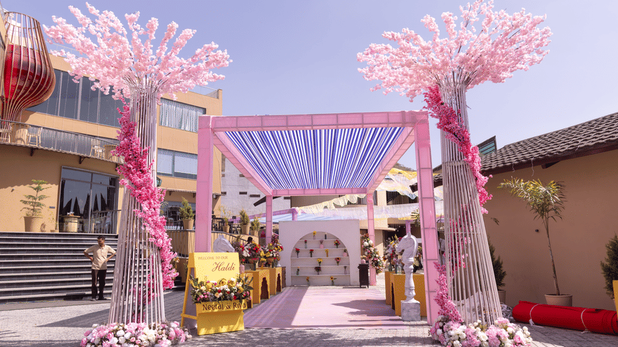 A wedding venue is decorated with pink floral arrangements and draped fabrics  | The Qualia Resort Club & Brewery, Udaipur