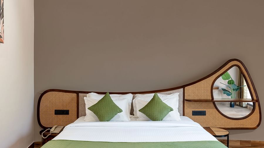 Luxury Villa with Sitout  featuring a close-up view of a king size bed with a wooden headboard, green and white bedding, and a decorative mirror on the wall at The Qualia Resort Club & Brewery, Udaipur.