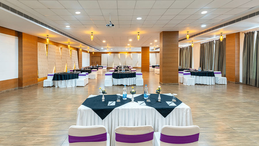 A larger empty event hall with white tables and chairs - Via Lakhela Resort & Spa