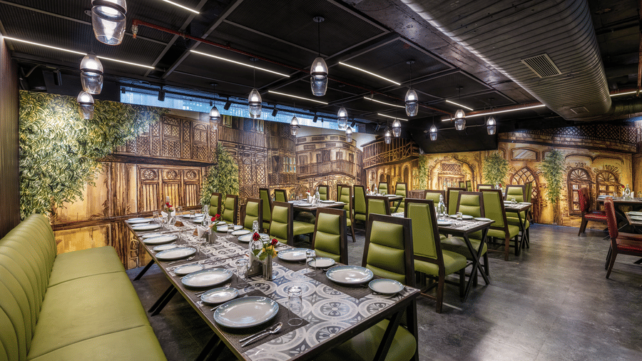 View of a private dining area at Lords Inn Amritsar with green chairs, long dining table, decorative wall murals, and warm ambient lighting.