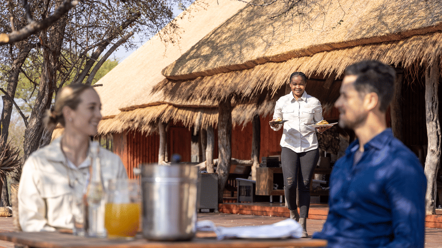 Guests enjoying sundowner drinks at the thatched bar at Evolve Back Kalahari