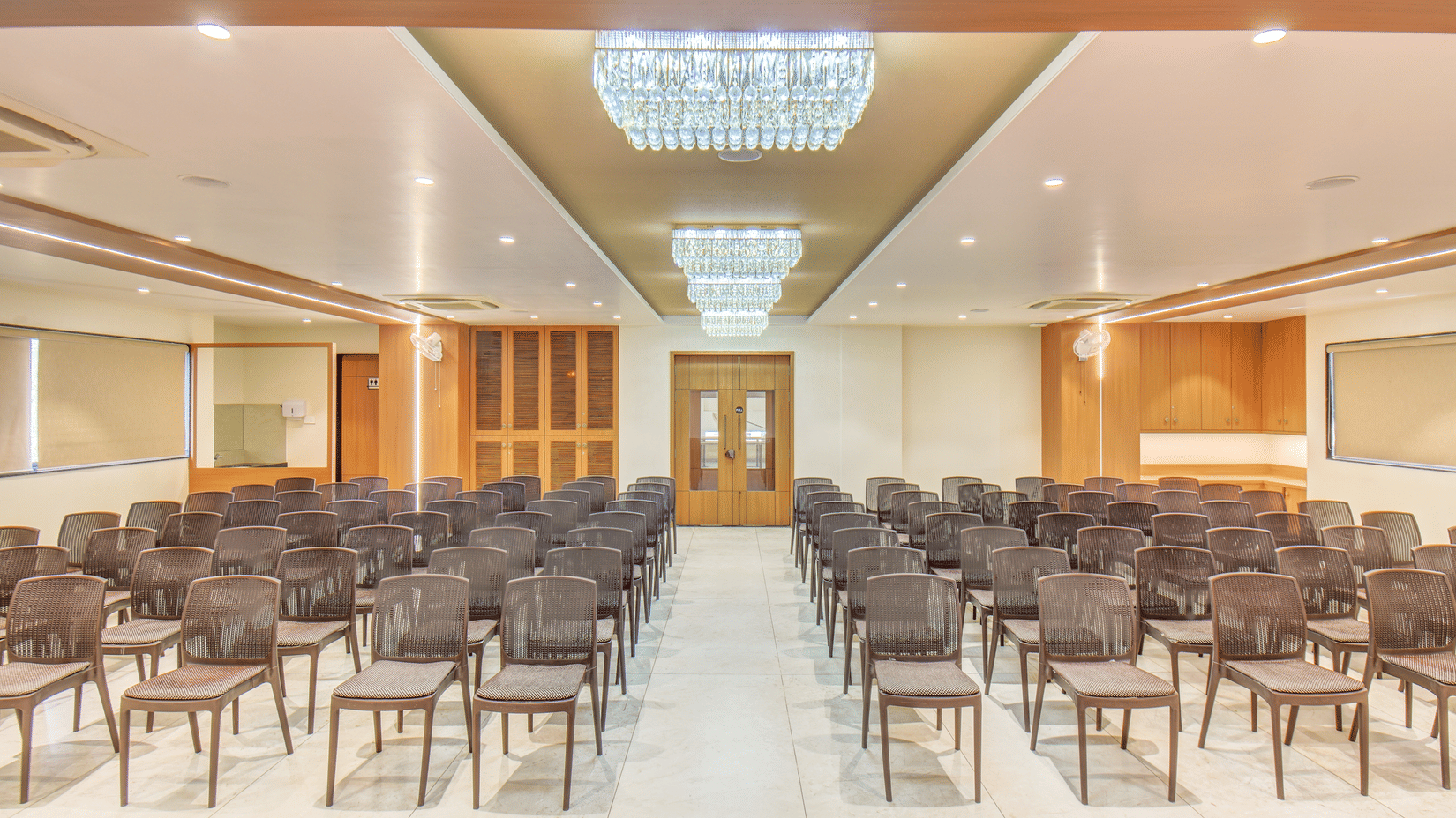 Ballroom at VITS Select Nashik Hotels & Resorts featuring chairs lined up under warm lighting and a door in the background