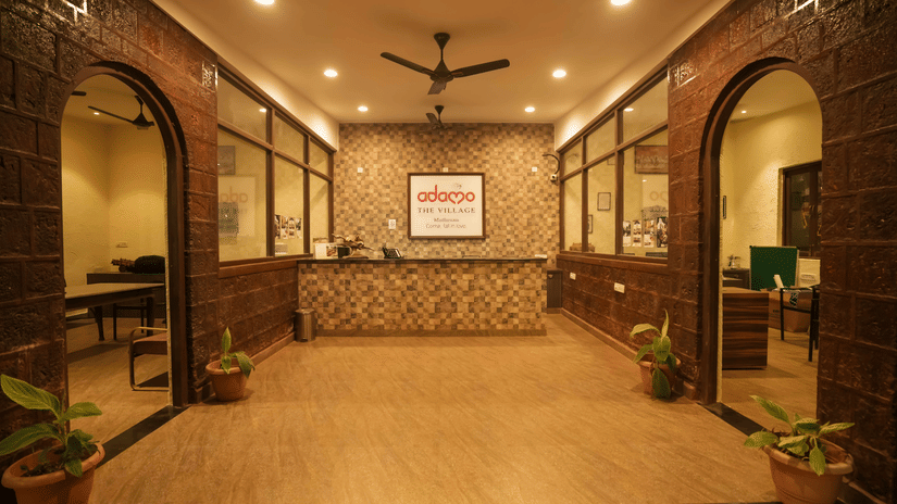 Interior view of the Adamo The Village reception area with a front desk, stone walls, and archways.