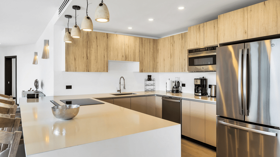 A kitchen at Tamarind Hills Resort and Villas, Antigua, with appliances, a kitchen island, a sink and wooden cabinets.
