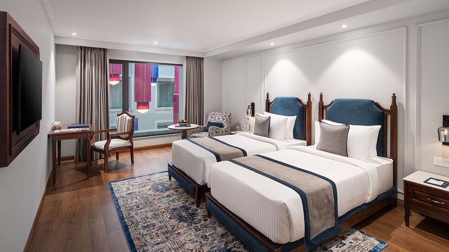 An image of the Superior Twin Room featuring large twin beds, a wall-mounted television, and a work desk - MJ Sarovar Portico, Haridwar