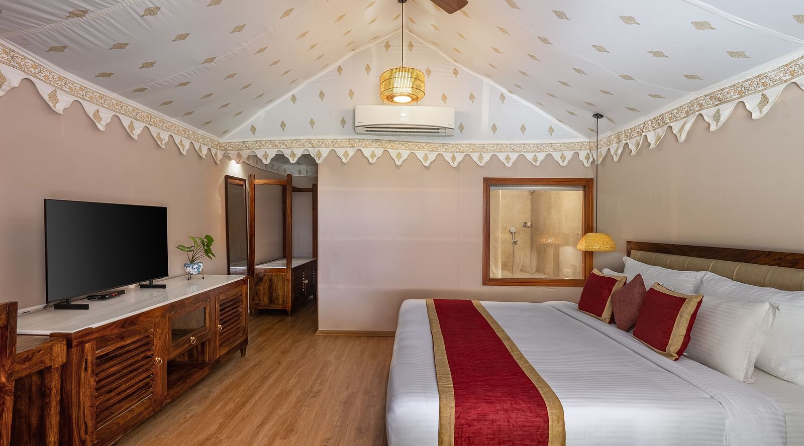 image of the luxury tent villa with high ceiling featuring a king size bed and a tv table with a television at aranya vilas
