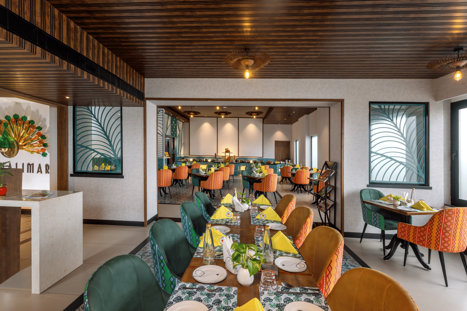 Dining space at Shalimar Restaurant in Zibe Luxe Hyderabad by GRT Hotels, offering colourful seating, ceiling lights, artistic decor, and best food in Hyderabad.
