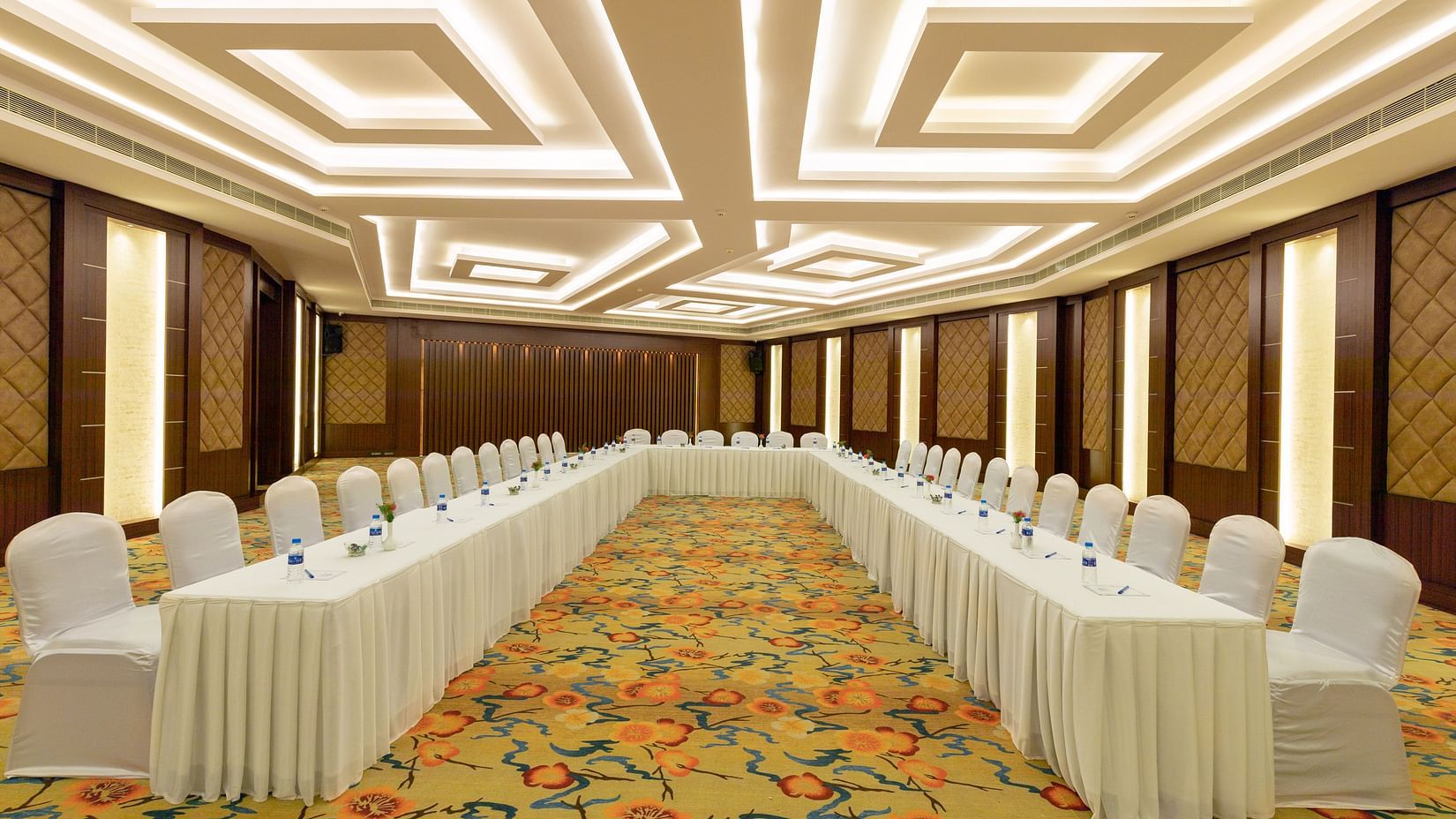 Elegant Jade Room with U-shaped table arrangement and chairs. The room features patterned carpet, wood-paneled walls, and bright, geometric ceiling lights