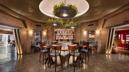 A bar area at Shilton International, Kochi, with a central round bar, stools, and hanging plant decorations.