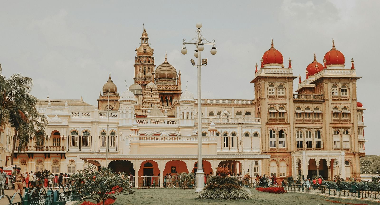 A facade image of the Mysore Palace with a green garden in front of it