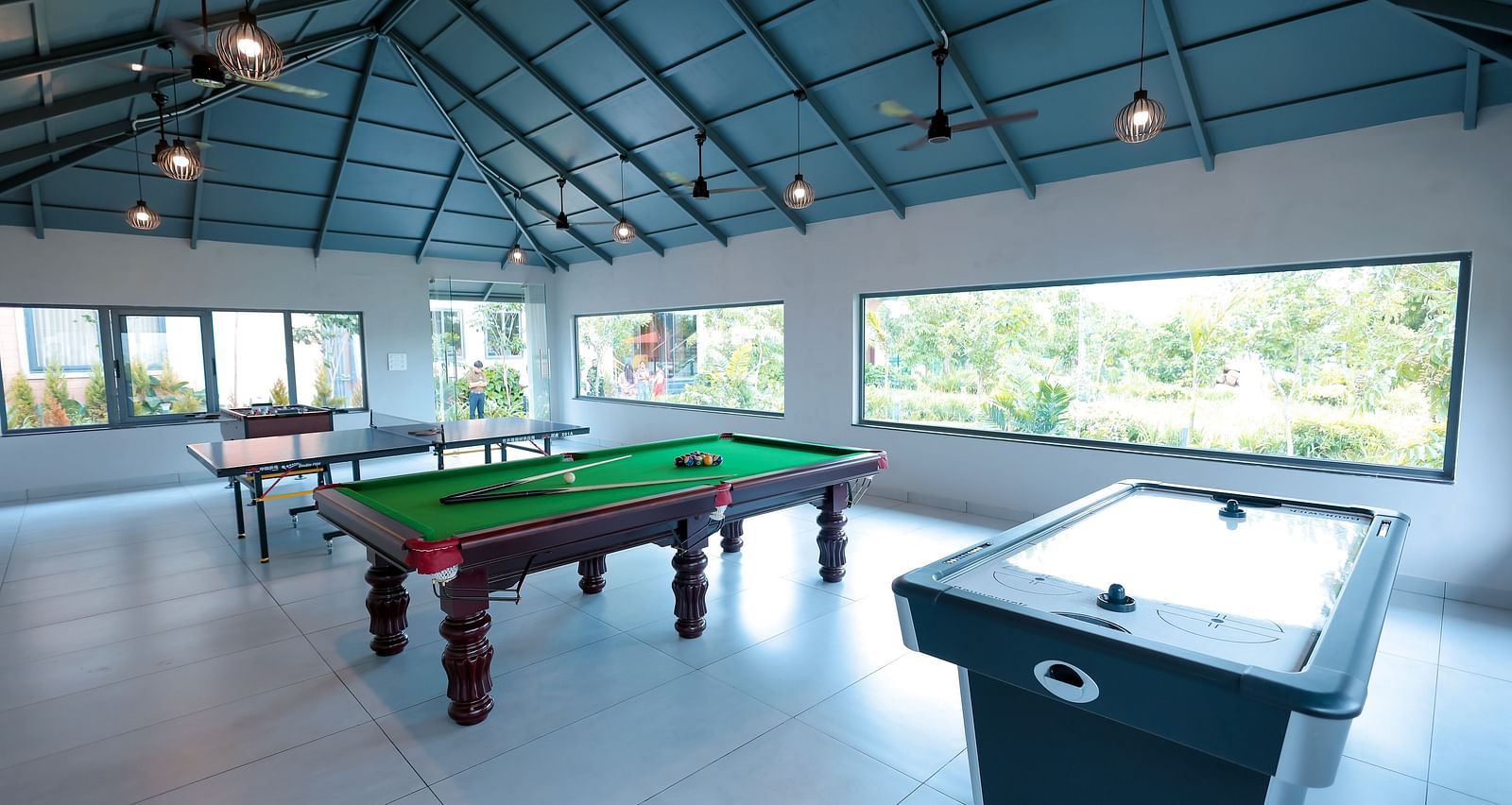 Recreation room with snooker and foosball tables under sloped roof at Trishvam Symphony, Krishnagiri.
