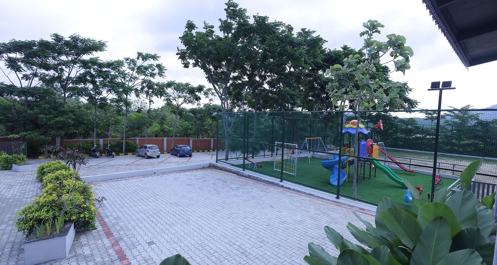 Outdoor play area with slides and greenery at Trishvam Symphony, Krishnagiri.