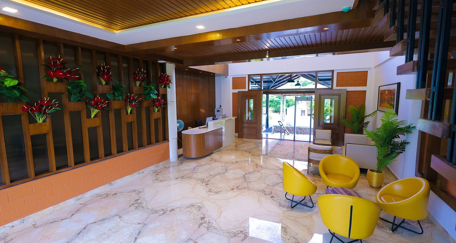 Reception area with marble flooring, yellow chairs, and vertical garden wall at Trishvam Symphony, Krishnagiri.