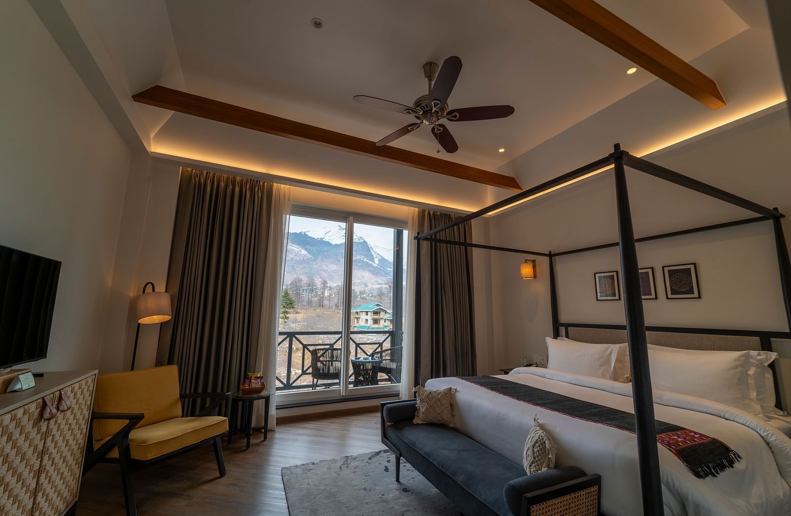 Bedroom with a four-poster bed, seating, and wooden beams at Nivasana Manali.