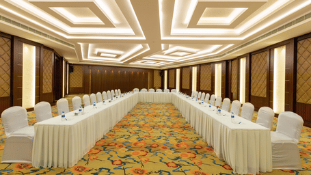 Elegant Jade Room with U-shaped table arrangement and chairs. The room features patterned carpet, wood-paneled walls, and bright, geometric ceiling lights