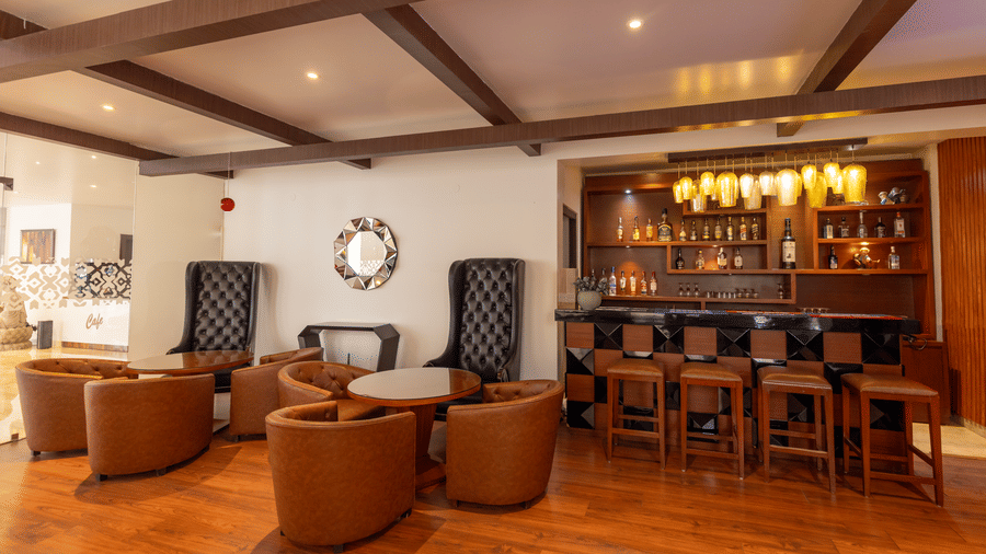 A seating area with chairs, tables, and a bar counter visible inside the room at Indraprastha Resort & Spa, McLeod Ganj.
