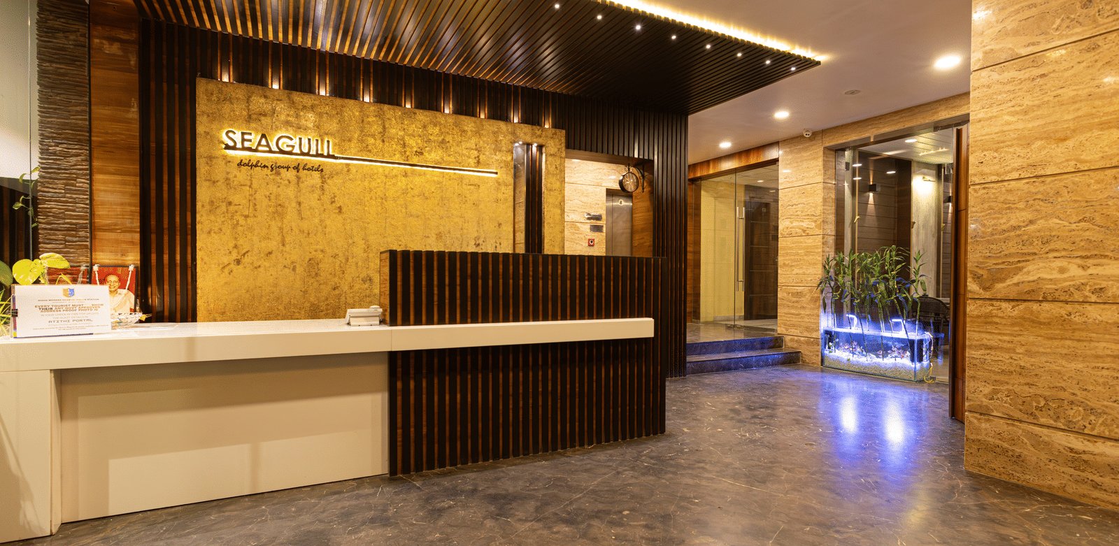 A reception area with front desk, seating space, ceiling lights, and wall decor at Hotel Seagull Digha.