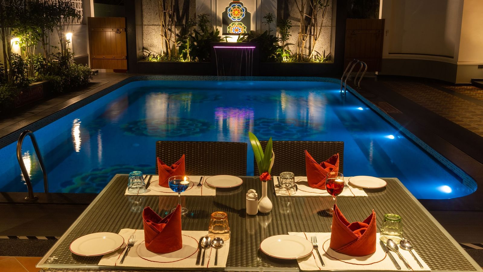 Tranquil pool with artistic tile design and lush greenery at dusk. Regency Madurai by GRT Hotels
