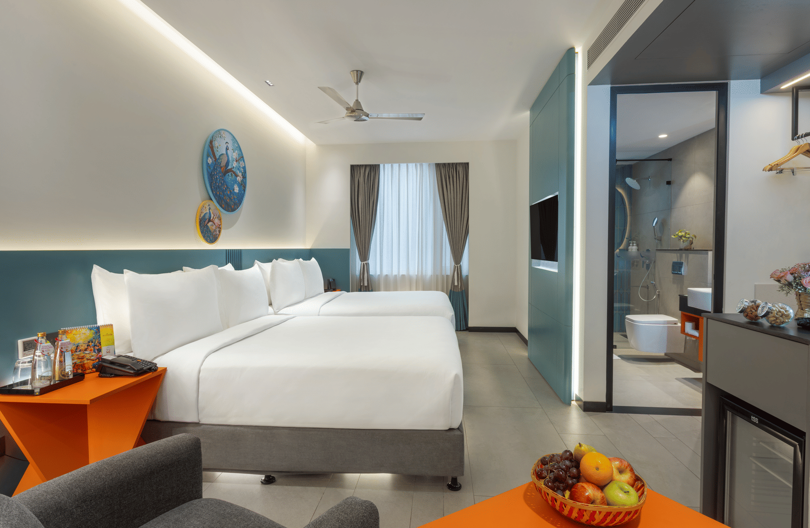 One of Zibe's hotel room in JP Nagar, Hyderabad, featuring twin beds, an attached washroom, a wall-mounted television, and a night stand.