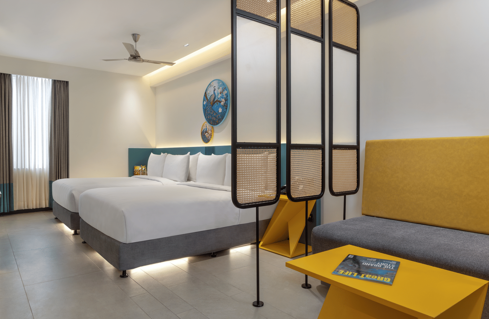 A neatly arranged room featuring 2 beds, a partition, a couch and a coffee table | Zibe Luxe Hyderabad by GRT Hotels 