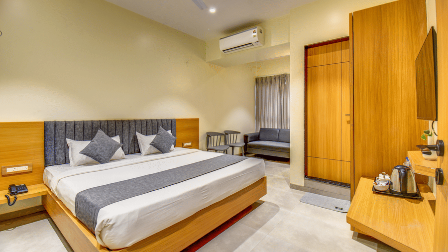 Executive Room at VITS Select Nashik Hotels & Resorts featuring a plush bed facing the TV on the wall under which a tea and coffee maker is placed on a wooden surface