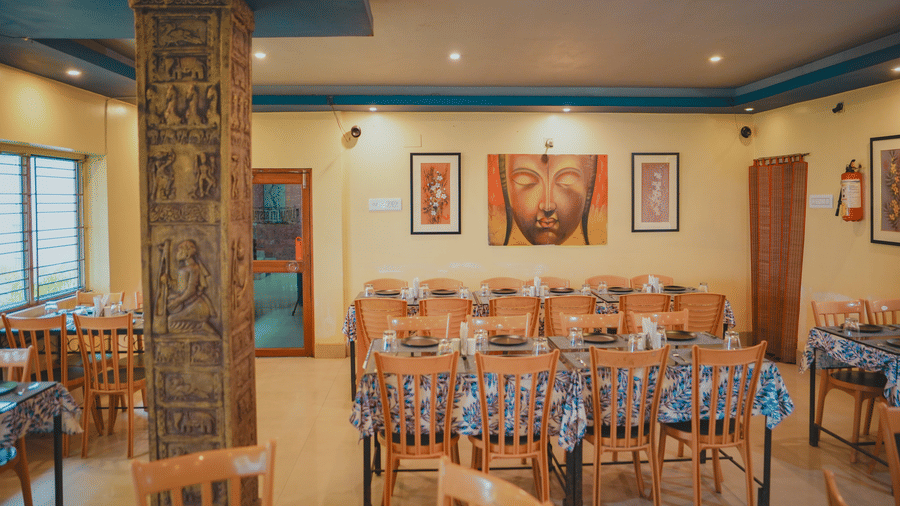 An indoor hotel restaurant banquet room featuring long tables with blue tablecloths and carved stone pillars.